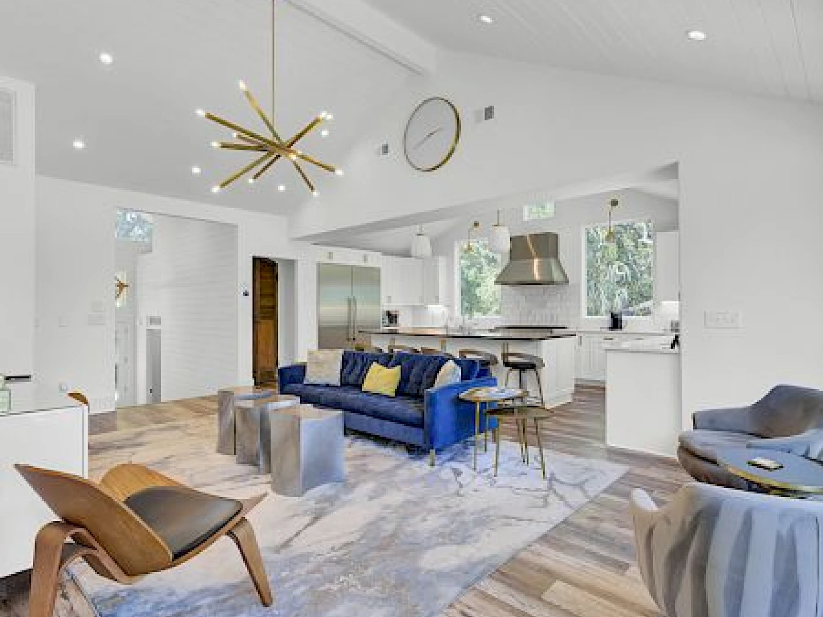 A bright, modern open-plan living area with a blue sofa, gold star chandelier, and a sleek kitchen; airy, stylish, and airy.